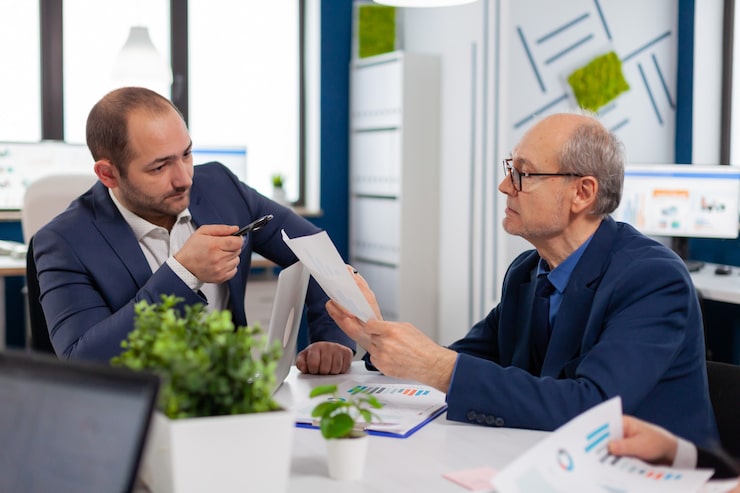 Senior entrepreneur explaining business financial strategy to coworkers in a briefing session